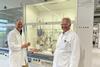 The founders of SBMatrices in a white lab coats standing and smiling before a fumehood